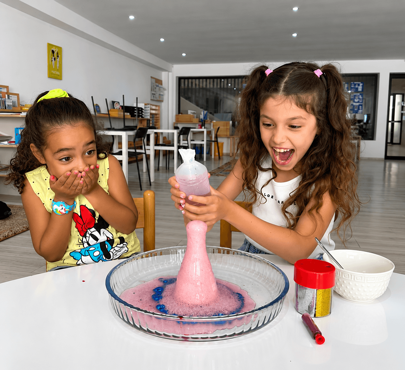 Two girls amazed by a foaming science experiment at camp