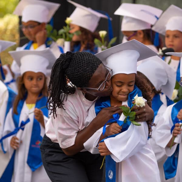 A teacher embracing a young graduate during the end-of-year celebration