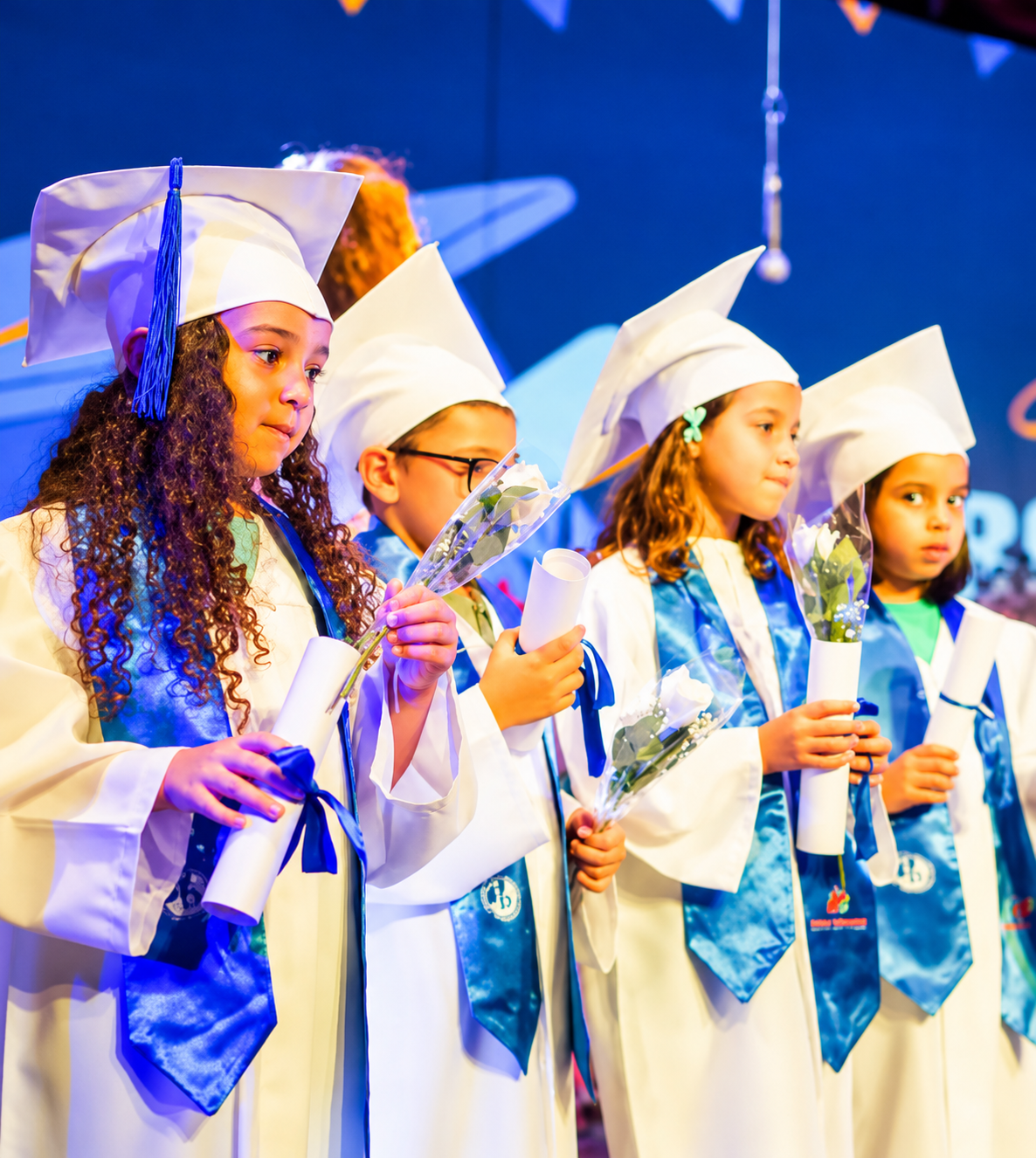 PYP graduates in caps and gowns holding their certificates