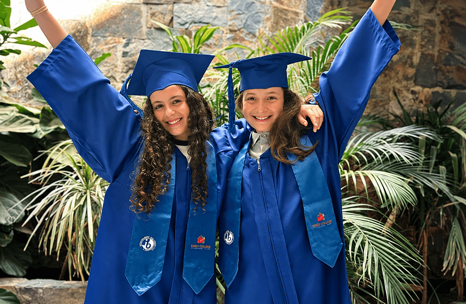 Two students celebrating in graduation gowns and caps