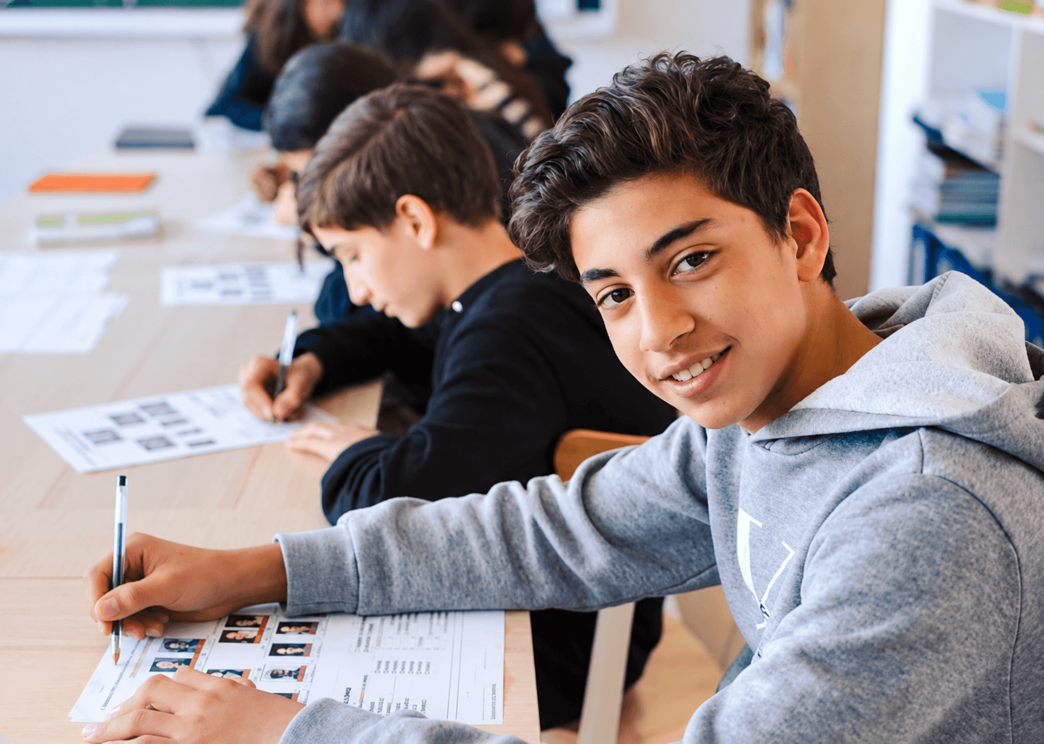 A middle school student smiling while working at his desk