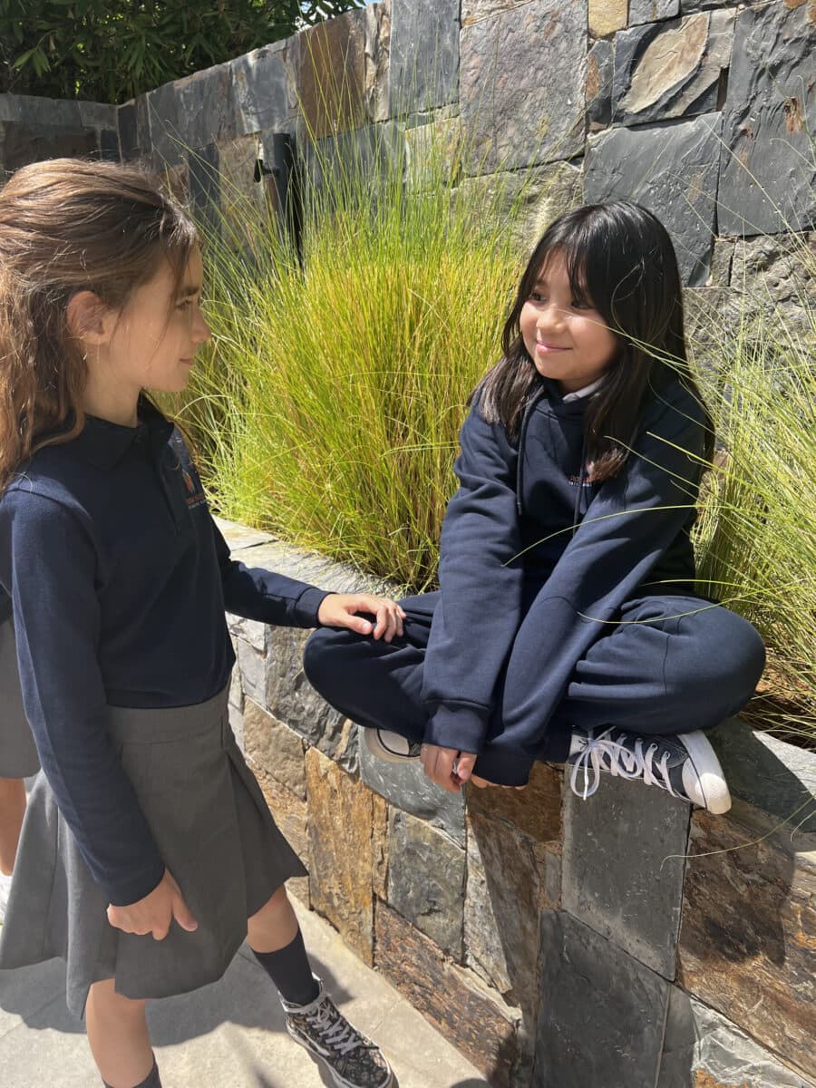 Two learners in navy uniform chatting in the garden