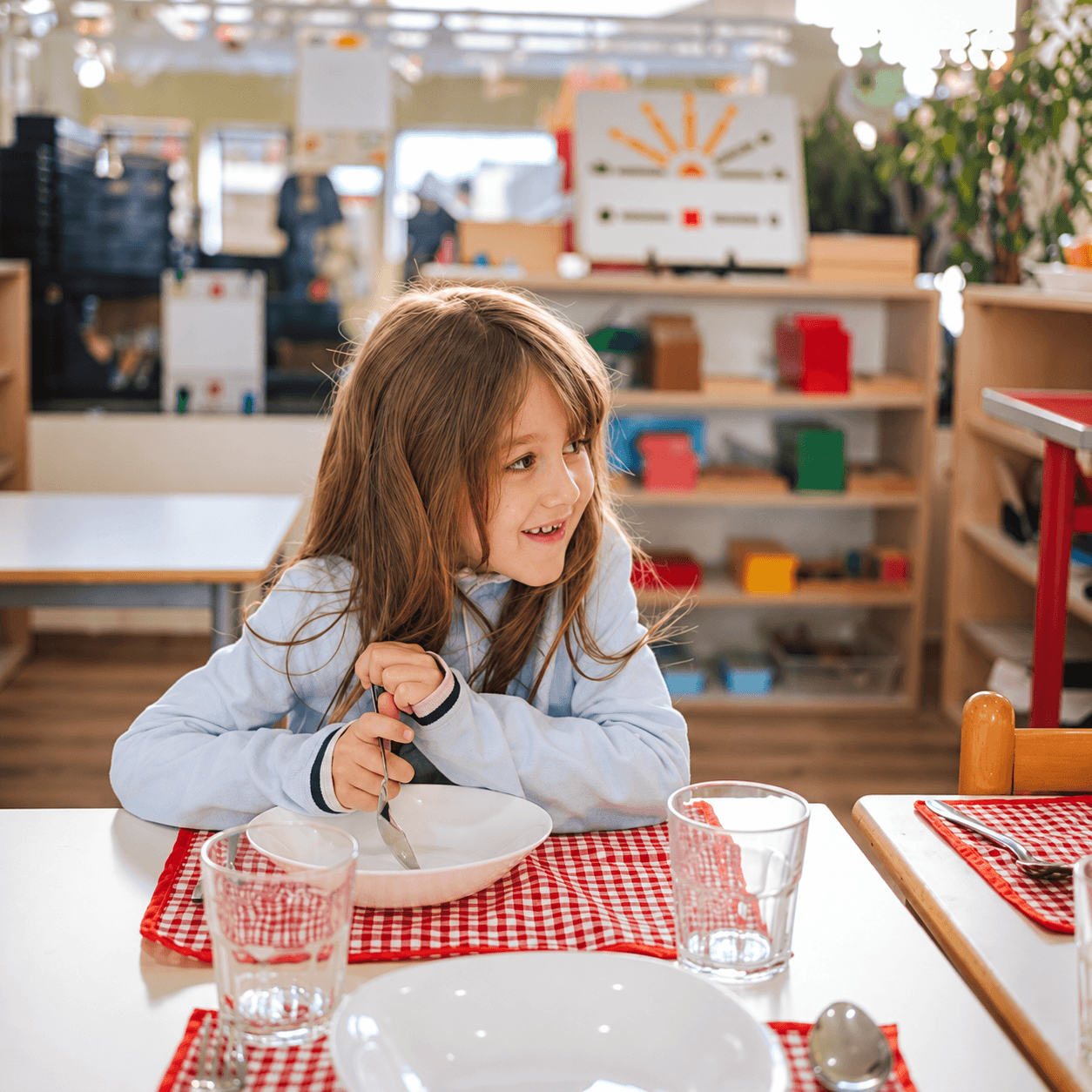 A young child enjoying lunch at a table set with a gingham placemat